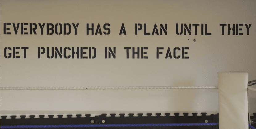 The quote: "Everybody has a plan until they get hit in the face" is displayed on a wall