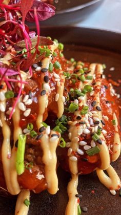 The Szechuan based sauce wings have white piso sauce poured over them and are garnished with vegetables.