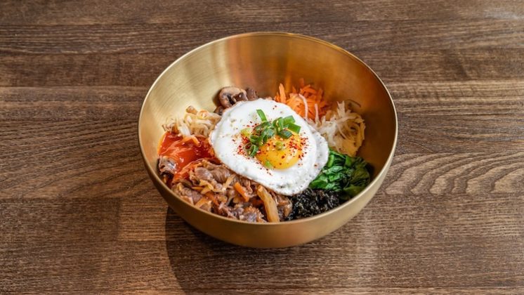 Dish Bibimbap in a golden bowl with sunny egg on the top.