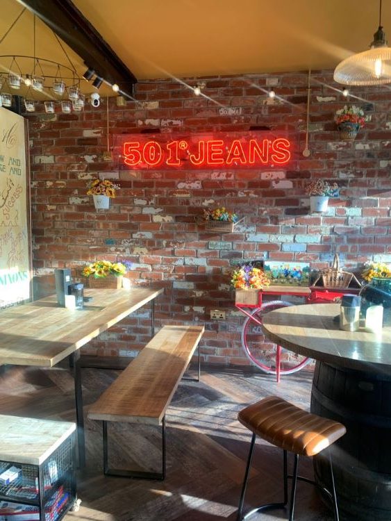 Neon 'Jeans' sign on Brick wall inside Nixon Coffee. 