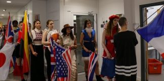 Models in outfits from first-year students being shown how to wave a flag and walk.