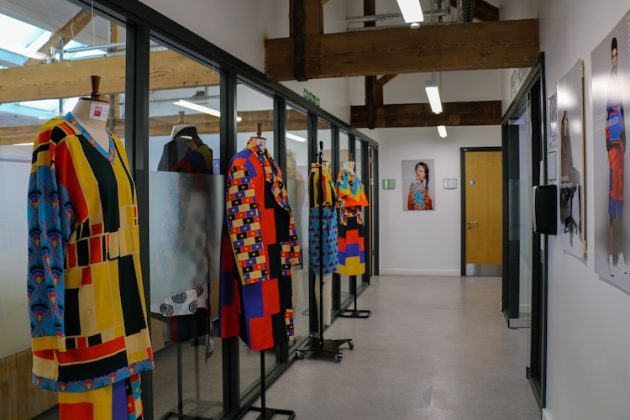 A hallway with colourful outfits showcased on the side.