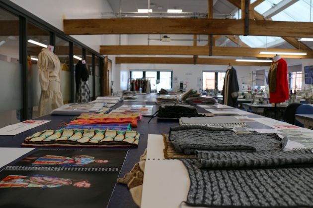 Students' portfolios on a huge wooden table showing the materials used for their collections.