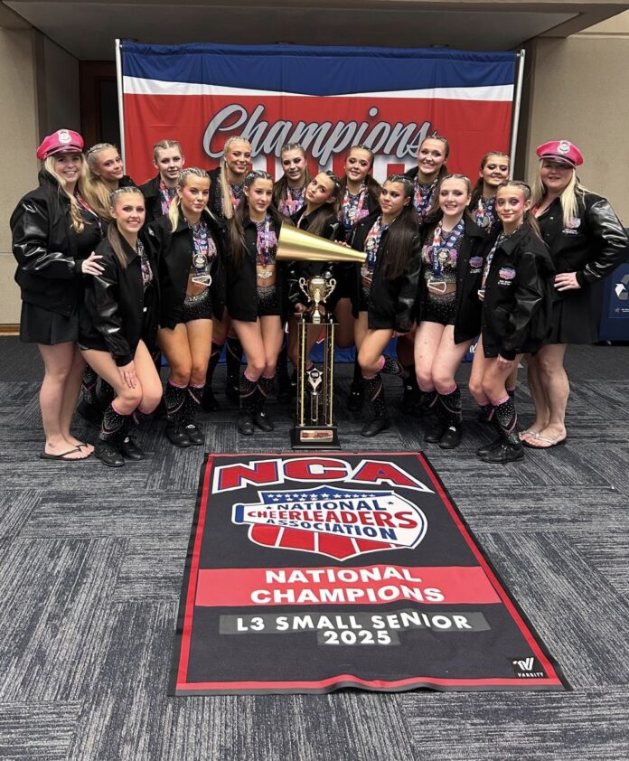 The photo shows Kent Cheer academy's Zirconium celebrating their win. They have their first places medals on and are posing with their coaches behind their trophy and winners banner.