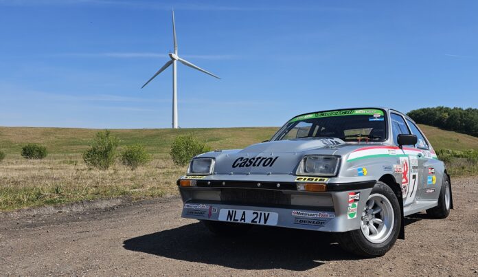 A Vauxhall Chevette Rally Car is seen parked in front of a wind turbine