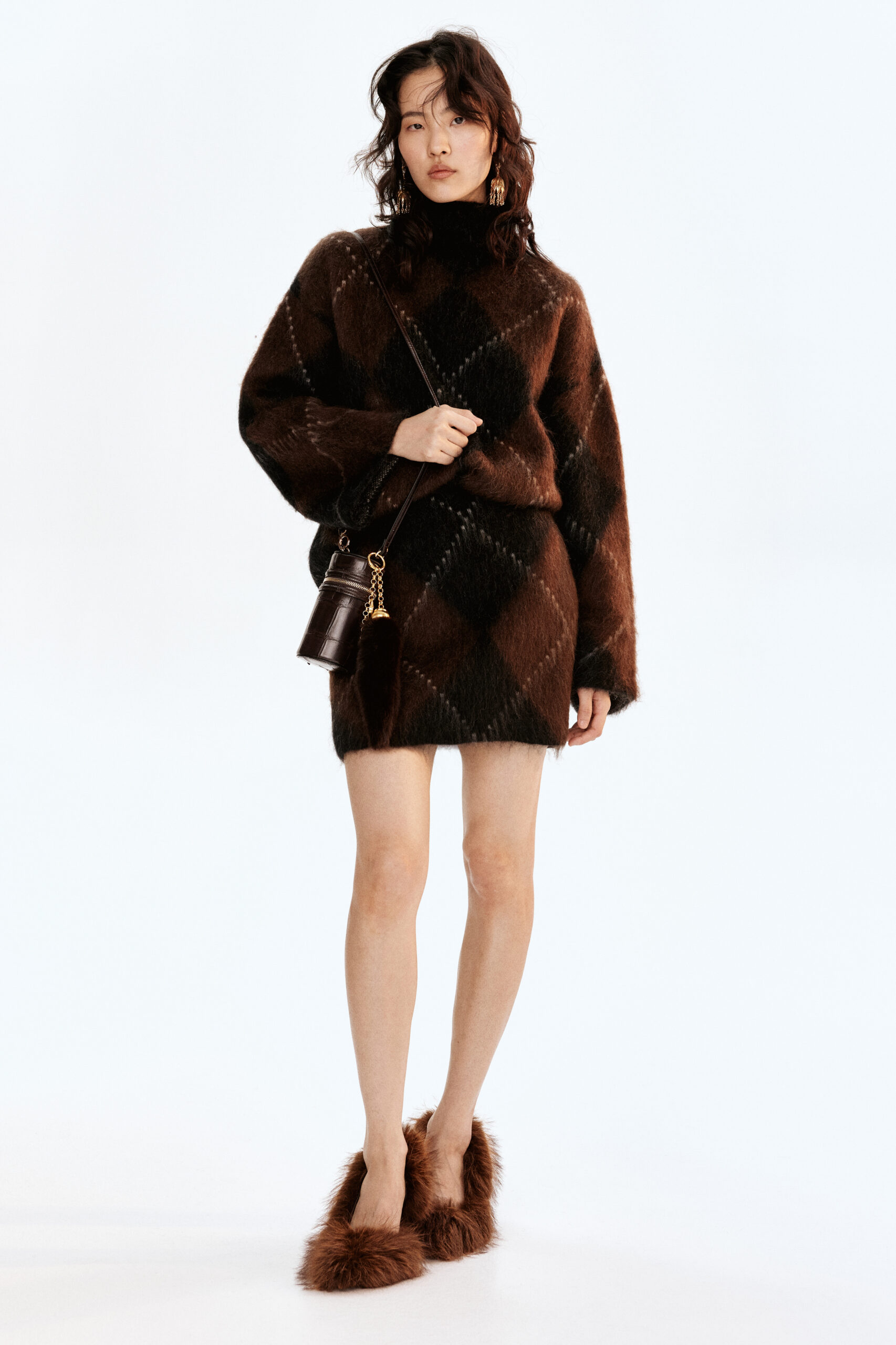 Model wearing oversized brown knit sweater styled as a dress, paired with faux-fur slip on shoes from H&M