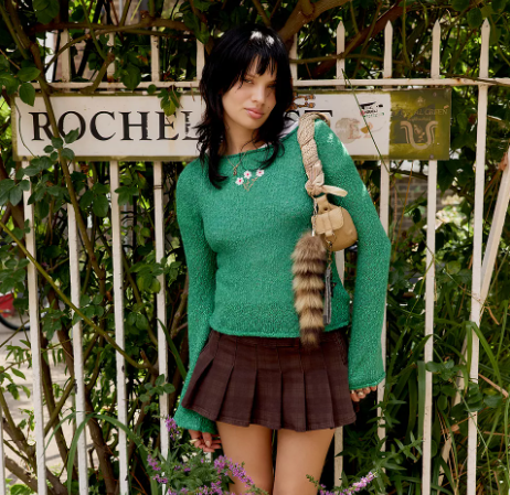 A person wearing a green sweater, brown skirt, and boots.