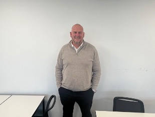 ProChance head of football and manager, Liam Sutcliffe, stands in front of a plain wall.